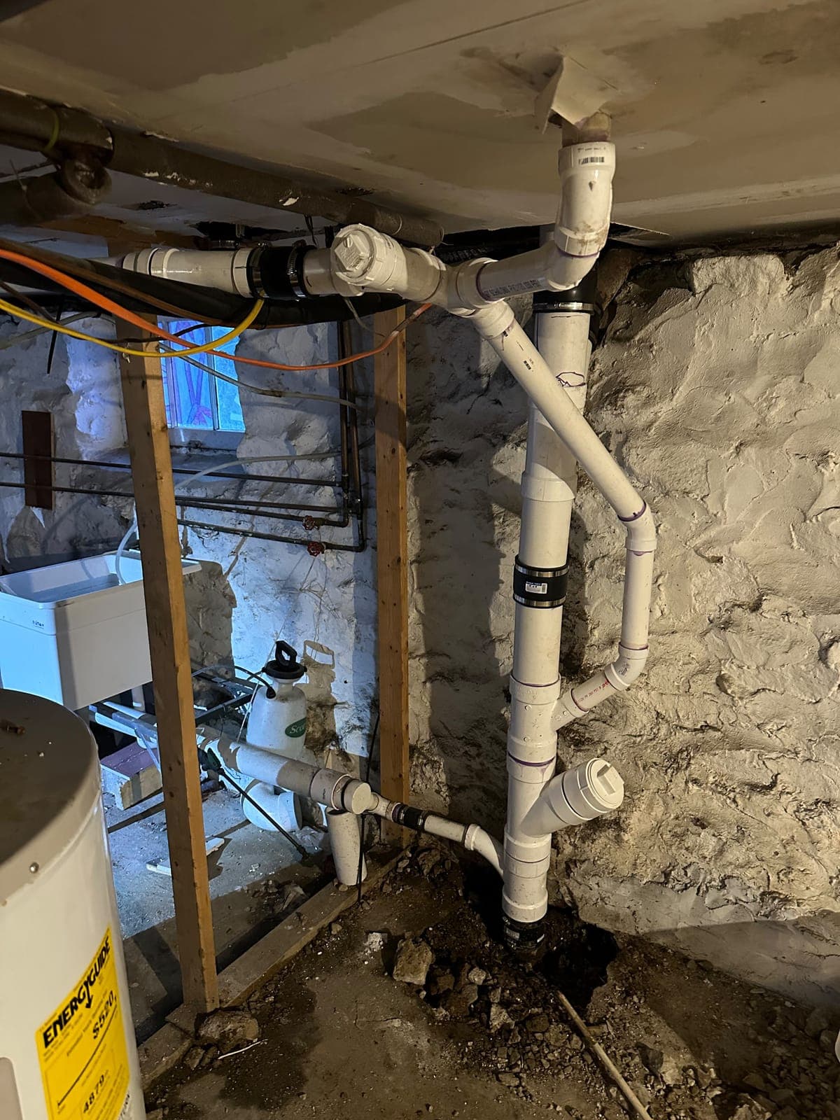 New PVC drain and vent piping in a stone-foundation basement