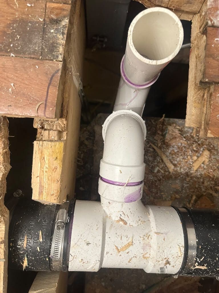New PVC drain fittings connected to existing pipe below the floor