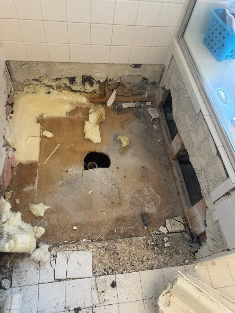 Shower area before repair: old base removed, exposing a water-damaged subfloor