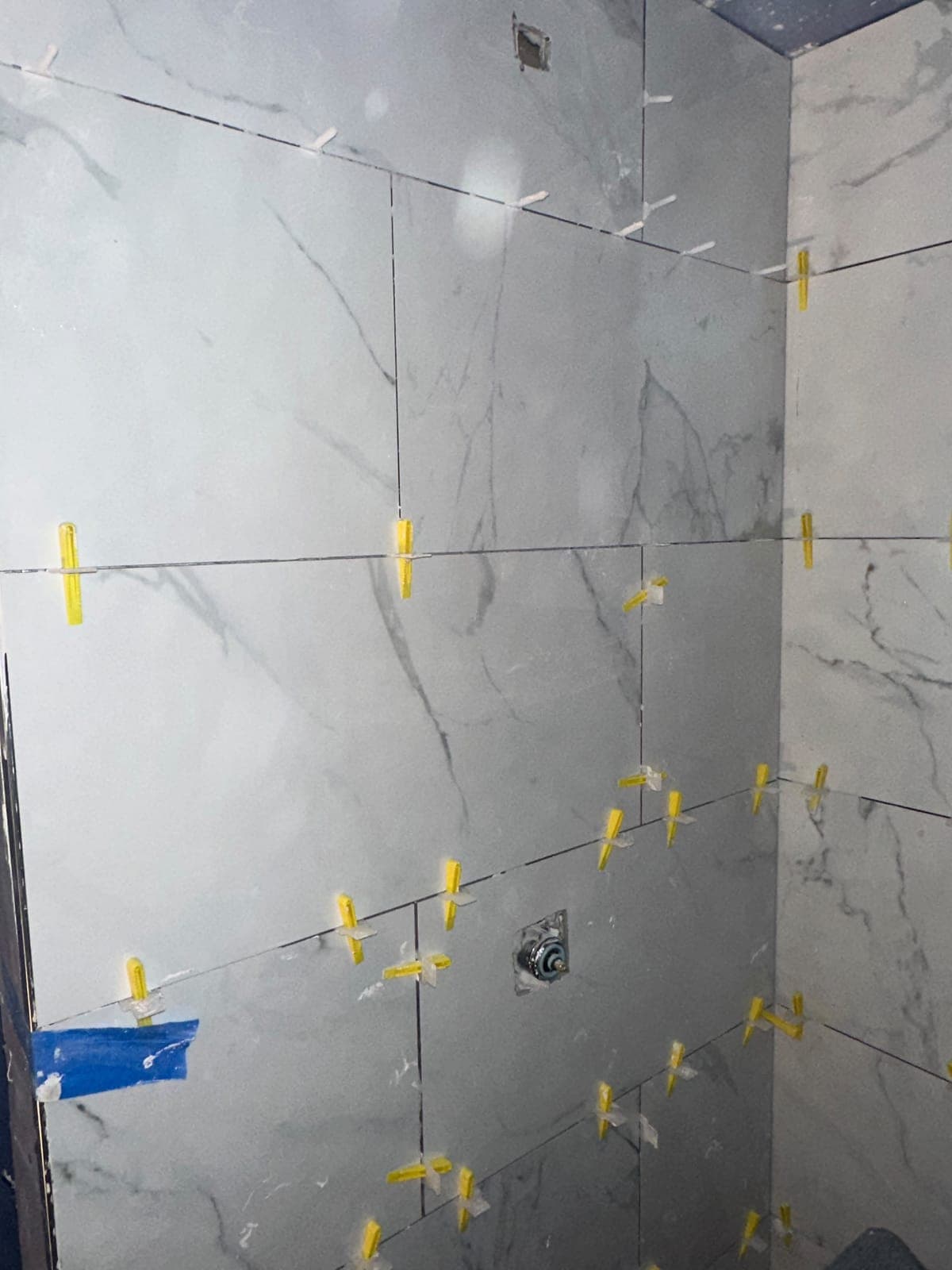 Large-format marble-look tile being installed on shower walls